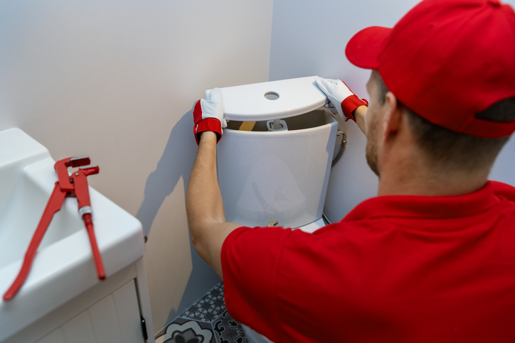 plumbing services plumber working in bathroom installing toilet wc water tank