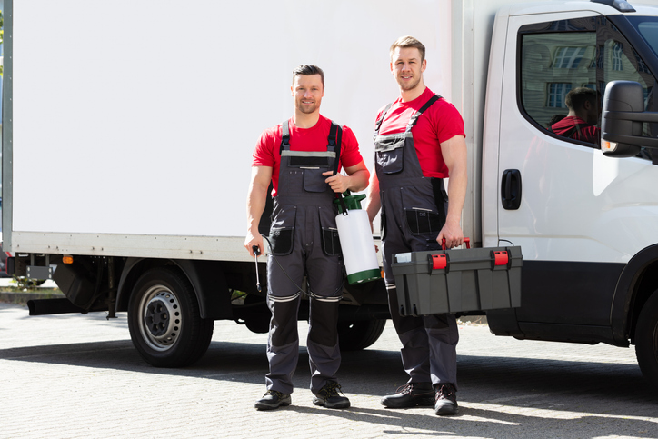 portrait of a smiling young male technicians holding tool box