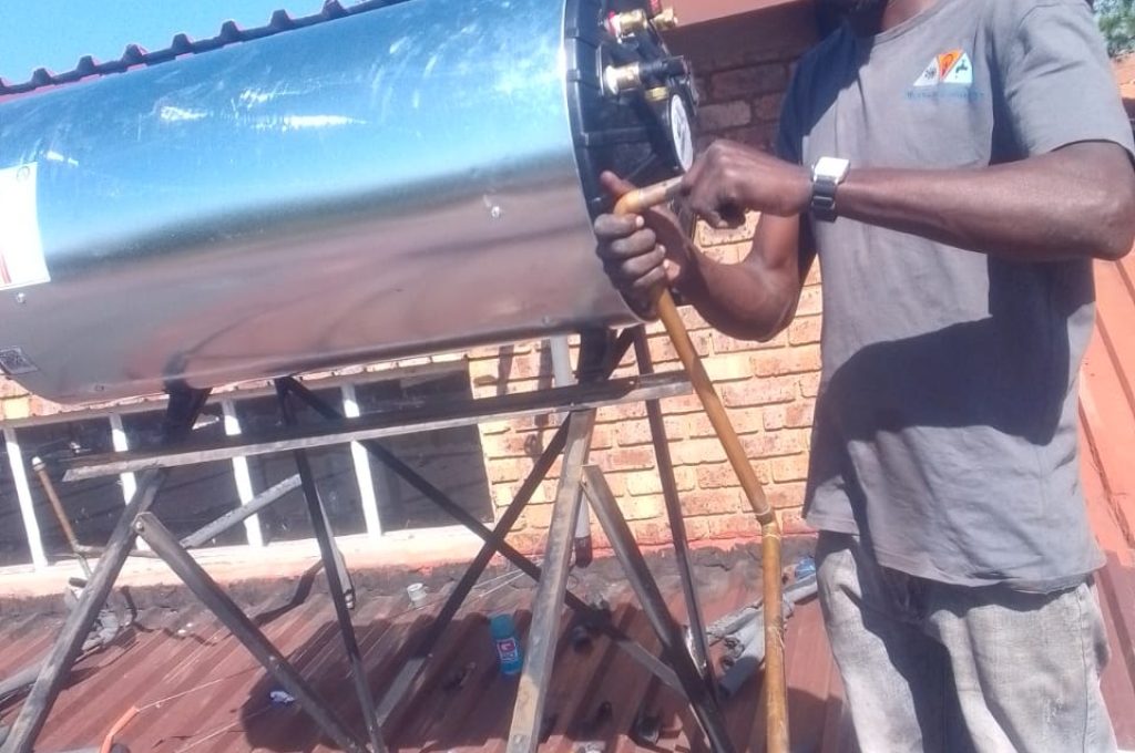 Technician adjusting a solar geyser, representing general plumbing services in Midrand.